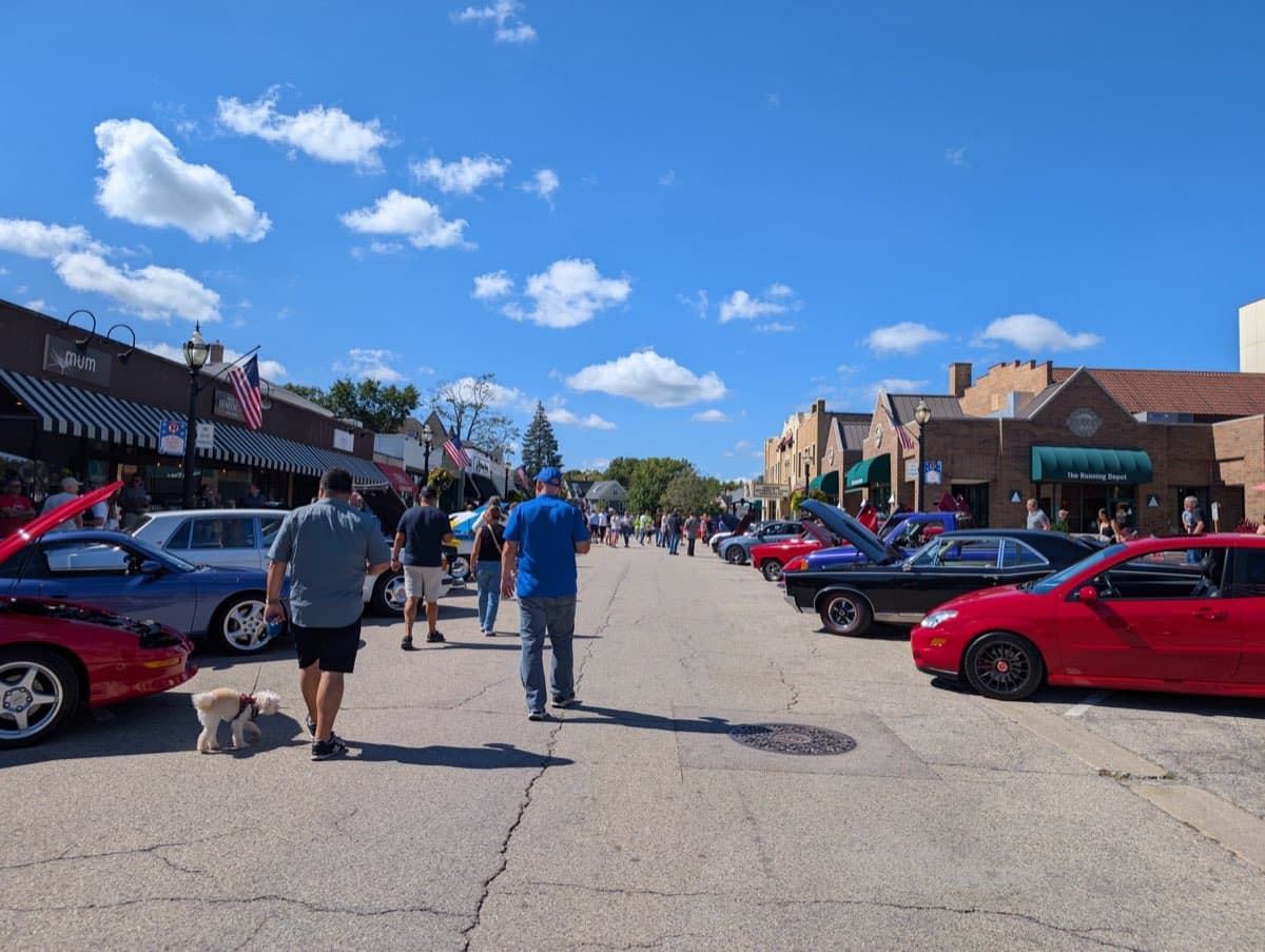 Street view with cars and spectators on a sunny day